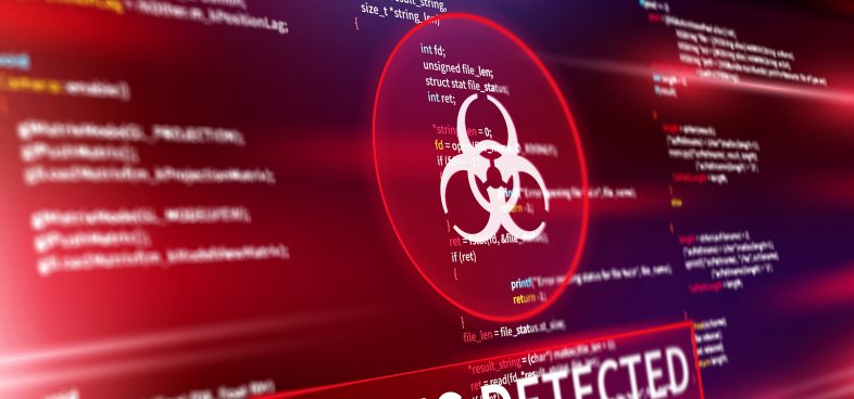 A close-up view of a computer screen displaying lines of code in red and pink shades, highlighting a central circular warning icon with a biohazard symbol. The word 'DETECTED' is prominently displayed in the lower right corner, indicating a cybersecurity alert and the end of a phrase.